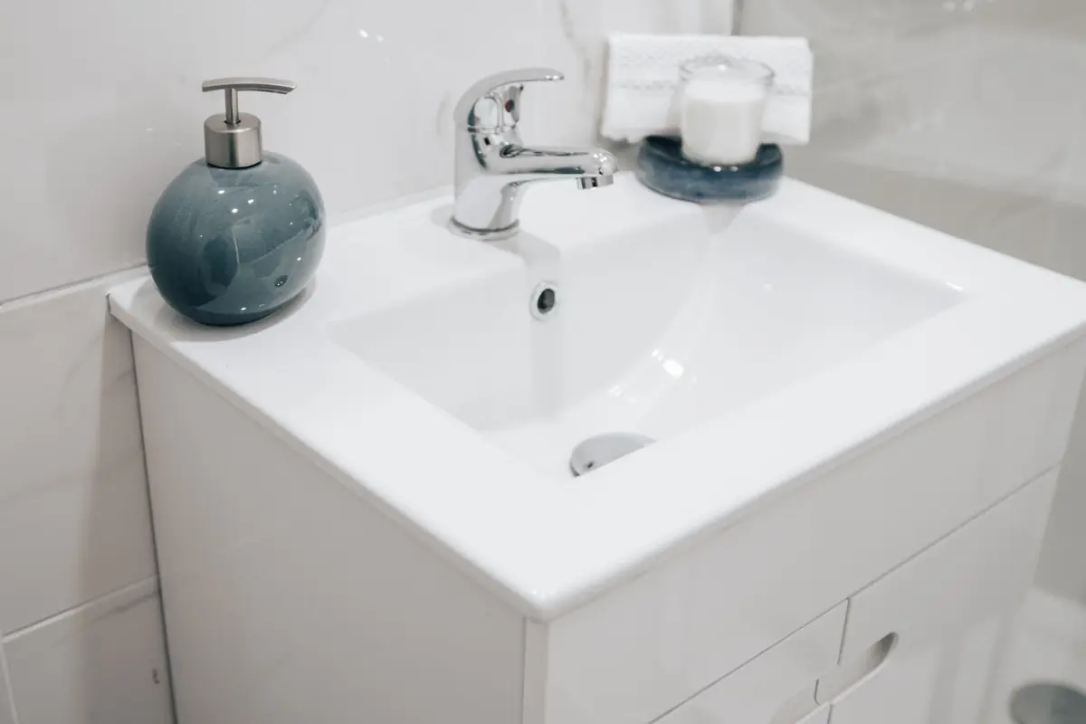 A newly fitted white basin and vanity unit with a chrome mixer tap and a soap dispenser.